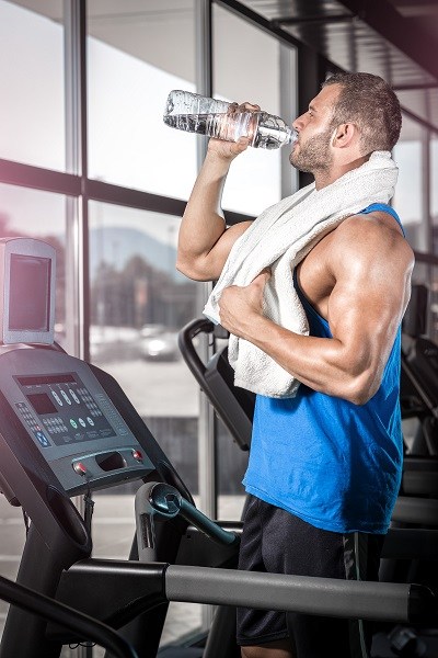 Young man drinking water in gym